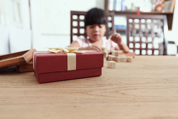 Red gift box placed on the table with the kid play a game sittin