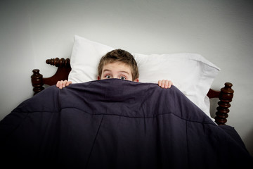 Boy hiding in bed