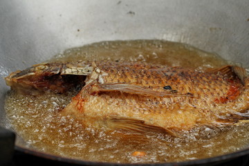Cooking of deep fried Nile tiapia fish.