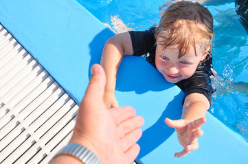 Schwimmunterricht - Papa rettet seine kleine Tochter  aus dem blauen, tiefen Wasser 