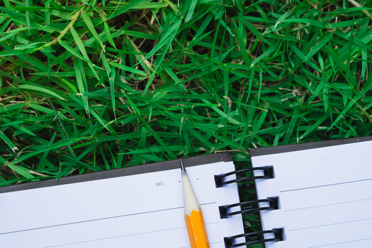 To do list in notebook - reminder notebook with pencil on space green field grass in flat lay, to do reminder write down on notebook with pencil, simple task list reminder on nature green field - Powered by Adobe