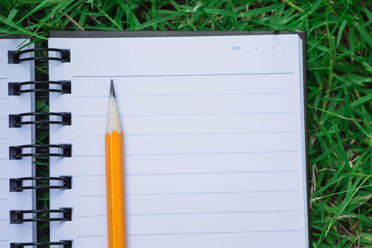 To do list in notebook - reminder notebook with pencil on space green field grass in flat lay, to do reminder write down on notebook with pencil, simple task list reminder on nature green field