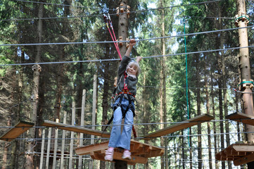 kleines Mädchen klettert mutig im Kletterwald