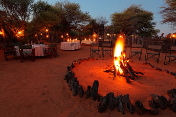 Nighttime campfire and decorated tables for outdoor safari catering . © EcoView
