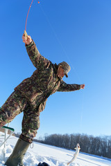 One european man is happy about holding catched fish on winter fishing at sunny day
