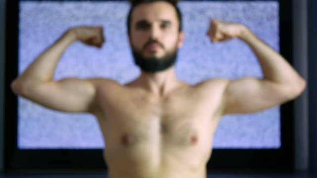 Happy self-confident bearded naked man showing his strong body with large grainy screen on the background.
