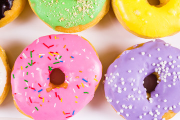 Colorful round donuts in the box. Flat lay, top view.