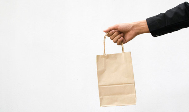 Brown Bag,Hand Holding A Paper Bag Isolated On White Background. Delivery Concept
