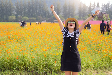 happy young woman enjoying summer in yellow field at sunlight with blur traveler background