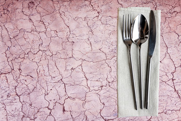 Concept of simple organic food - laconic design cutlery set on old rose marble background with cracks.