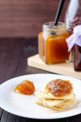 Crackers with orange jam on wooden background