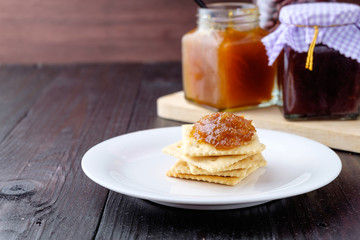 Crackers with orange jam on wooden background