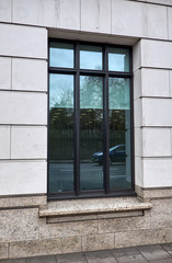 Big rectangular black window in an office building facade with ashlar walling