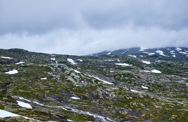 The rough terrain with water from melted snow, moss, exposed granite and low hanging clouds, on the way to Stordalsnibba