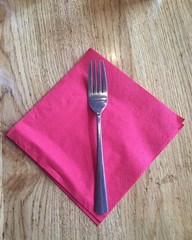 Silver fork and red tissue paper on wood table