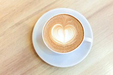 Cup of Cappuccino Coffee with heart pattern in a white cup on wooden background