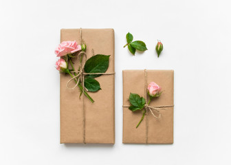 Naklejka na ściany i meble Gift boxes in eco paper on white background. Presents decorated with roses. Holiday concept, top view, flat lay