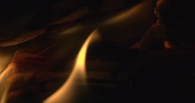 A log burner with slow flames and rising embers. Filmed in slow motion 4K