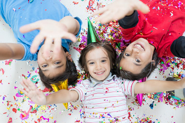 Happy kids celebrating party with blowing confetti