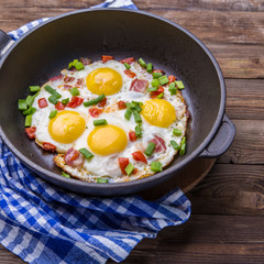 Fred eggs in pan with tomatoes and green fresh onion.