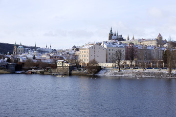 Fototapeta premium Snowy freeze Prague Lesser Town with gothic Castle above River Vltava, Czech republic