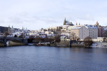 Obraz premium Snowy freeze Prague Lesser Town with gothic Castle above River Vltava, Czech republic