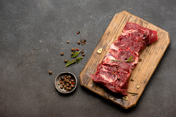 Raw meat with spices and rosemary on wooden board. Fresh beef. Ready to roasting. Top view.