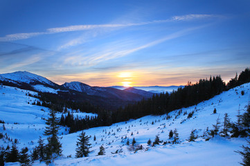 Fototapeta na wymiar Sunset in winter Carpathians. The setting sun, painted in warm colors covered with snow slopes.