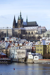 Obraz premium Snowy freeze Prague Lesser Town with gothic Castle above River Vltava, Czech republic