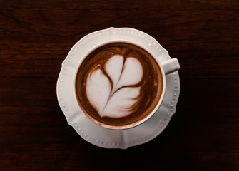 Closeup cup of hot coffee tulip latte art on wood table, vintage