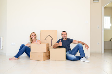 happy young couple carrying cardboard boxes moving into their new house