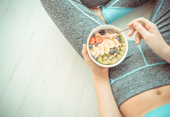 Young woman is resting and eating a healthy oatmeal after a workout. Fitness and healthy lifestyle concept.