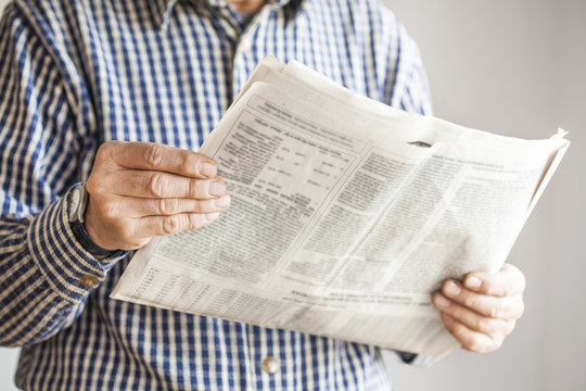 Man reading newspaper on gray background