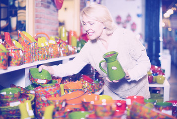 Woman customer holding  ceramic cookware at workshop