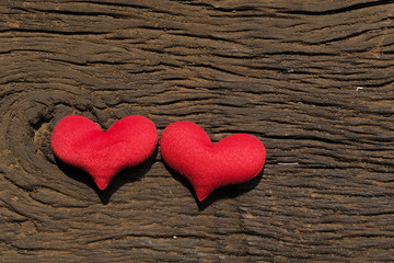Two red hearts on old shabby wooden background with sunlight