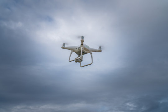 Flying drone with cloudy sky background controlled by professional photographer
