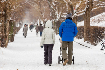 Fototapeta na wymiar People in winter walk in the Park. Young parents with a baby stroller. Snow