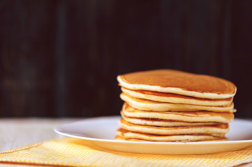 Pancake on a white plate on a wooden background