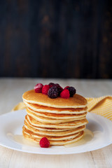 Pancake on a white plate with fruit on a wooden background