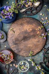 Board with fresh herbs and flowers, cup of tea and kitchen tools, top view, copy space