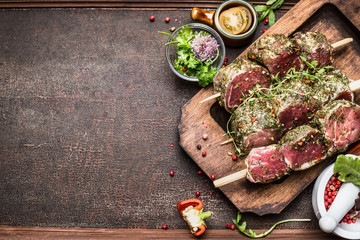 Tasty raw Meat skewers preparation with fresh delicious seasoning on rustic background,  top view, border