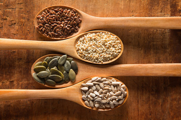 Food ingredients in wooden spoon on wooden background. Flax, pumpkin seed, sunflower seed, sesame and himalayan salt.