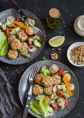Vegetarian lunch - quinoa meatballs and vegetable salad on a dark table, top view