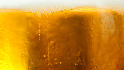 Glass of ice cold tasty beer with foam close up. Fresh lager or white beer with bubbles on the brewer in the beer pub