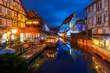 Fototapeta na wymiar Traditional Alsatian half-timbered houses and river Lauch in Petite Venise or little Venice, old town of Colmar, decorated and illuminated at christmas time, Alsace, France