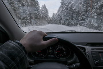 Driver's point of view looking through car windshield of snowy road, winter driving, forest trees covered with snow