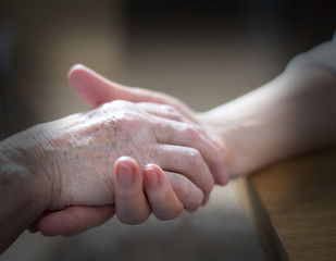 Hand einer alten Frau wird gehalten