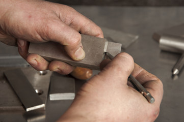 Man`s hands with metal stylus pointing out on a piece of metal