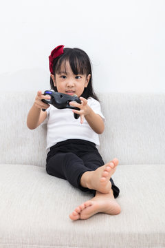 Asian Chinese little girl playing TV games on the sofa