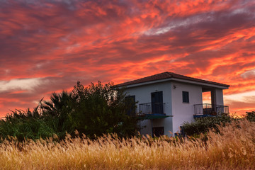 Fototapeta na wymiar Colorful vivid sunrise at Cyprus with house and dramatic sky